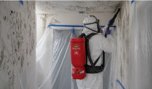 Worker in protective gear vacuuming a ceiling with the Enviromaster Probe 10 HEPA backpack